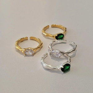 Detailed shot of irregular texture rings with oval green and white zircon stones