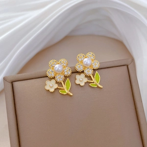 Detail of luxury floral earrings with gold plating, white rhinestones and pearls