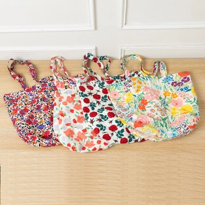 Detail showing four floral canvas tote bags with rose and wildflower patterns on wood