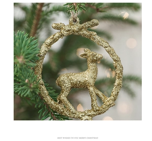 Close-up of golden glitter reindeer wreath ornament hanging on a festive pine branch