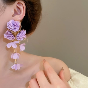 Close-up of lilac chiffon fabric flower tassel earrings worn on a model for a beach vibe