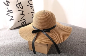 Detailed texture of woven straw hat featuring a black ribbon and elegant bow accent