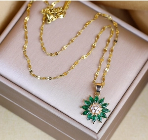 Detailed close-up of a gold daisy pendant with green petals and diamonds on silk