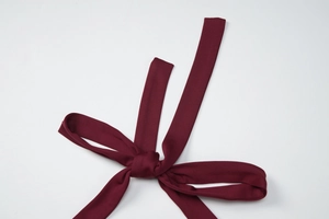 Detail of wine red fabric tie-up strap with plain weave texture and knotted design