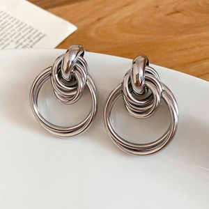 Detailed view of silver intertwined triple-loop knotted earrings with high-polish finish