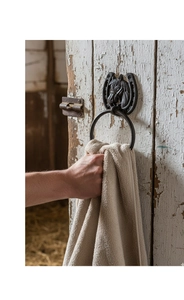 Close-up of hand using a vintage cast iron horseshoe towel ring with horse head detail