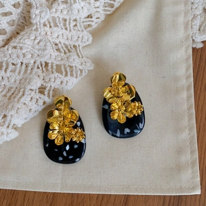Macro shot of ethnic vintage earrings featuring black resin base and golden 3D flowers