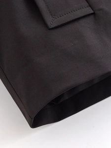 Close-up of black twill fabric texture and stitching detail on a double-breasted trench coat