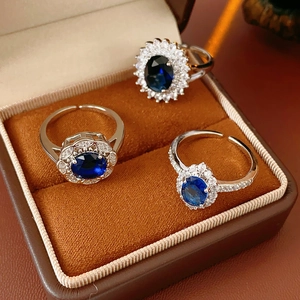 Detail of three blue zircon rings in a jewelry box featuring silver finish and open bands