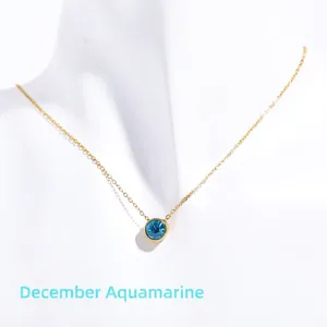Detailed view of gold necklace with round blue birthstone pendant on white model