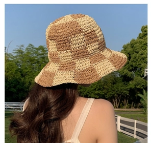 Outdoor view of a khaki and cream checkered crochet bucket hat for sun protection