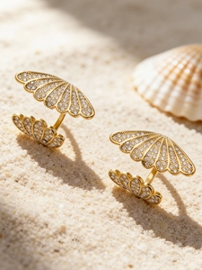 Macro shot of 18k gold plated shell-shaped rings with pave-set zircons on white sand