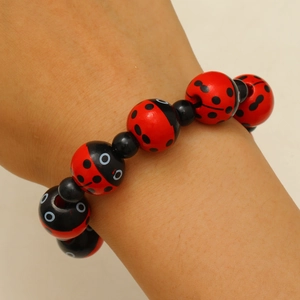 Détail du bracelet en perles coccinelle avec perles rouges et noires sur un poignet