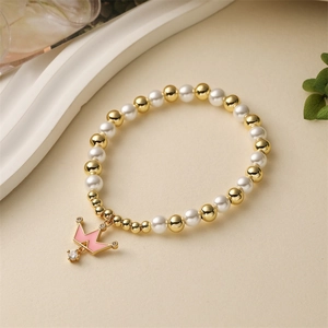 Detail of beaded bracelet with gold copper beads, pearls and pink crown pendant