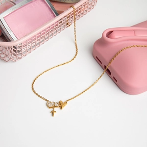 Detail of 18K gold plated necklace with rhinestone heart and cross pendants on white