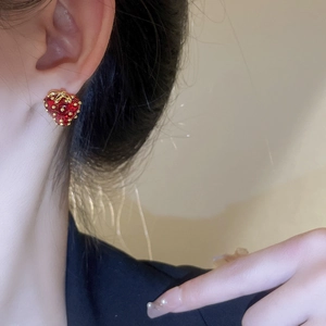 Close-up of red strawberry stud earring with gold leaf detail on female model's ear