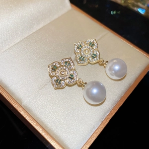 Detail of vintage flower stud earring with zircon accents and a dangling pearl pendant