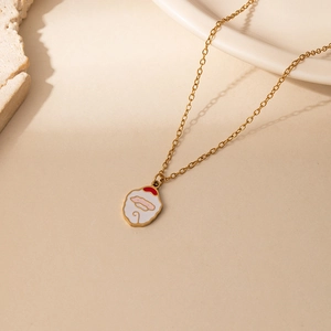 Close-up of golden stainless steel necklace with red and white Santa Claus pendant