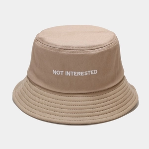 Dettaglio cappello a secchiello in cotone beige con ricamo a lettere bianche ricamate