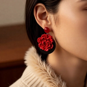 Close-up of vintage red flower earrings with black base on model in warm lighting