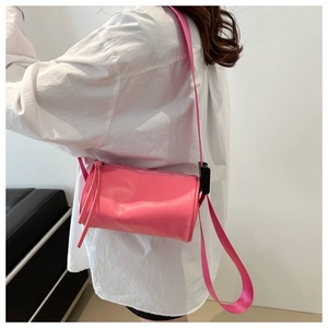 Dettaglio borsa a cilindro rosa con tracolla larga e cursore con nappine lunghe
