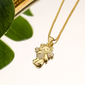 Macro shot of gold bear pendant with white cubic zirconia and green leaves on white background