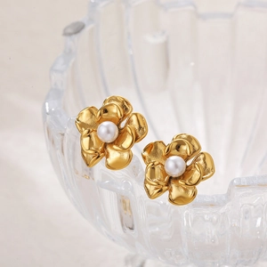 Detailed view of 18k gold plated flower earrings with white pearl center on glass stand