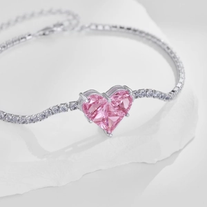 Detail of pink heart-shaped gemstone tennis bracelet with cubic zirconia and silver clasp