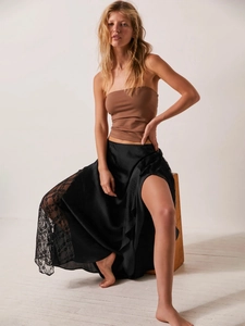 Detail of elegant black satin midi skirt featuring delicate lace patchwork and silky texture