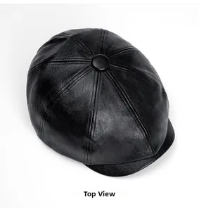Top view detail of a black faux leather newsboy cap showing fine texture and stitching