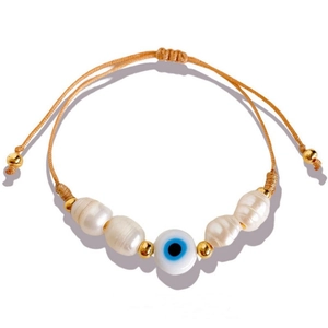 Handmade woven bohemian bracelet with baroque pearls and evil eye charm on white background
