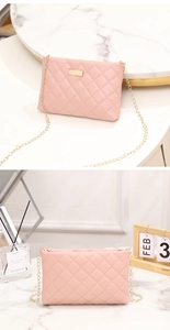 Detail of pink quilted crossbody bag with golden chain and metal buckle on marble surface