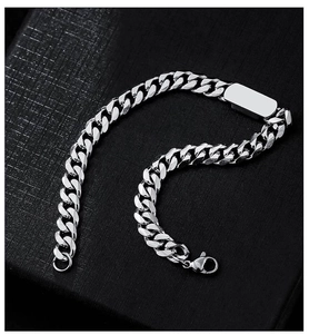 Detail of silver titanium steel Cuban chain bracelet with rectangular ID tag on black background