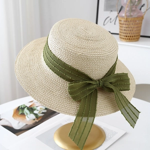 Detail of hand-woven straw boater hat with dark green polka dot tulle and bow decoration