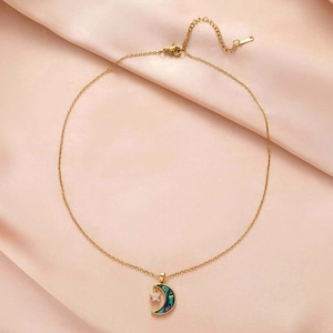 Detail of gold moon pendant with colorful shell texture and inset star zircon on silk fabric
