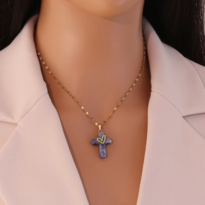 Detail of cross pendant necklace with green heart on model's neck for elegant styling