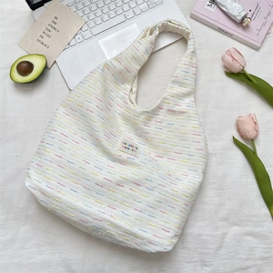 Detail of white knit tote bag with color specks, woven label and soft texture