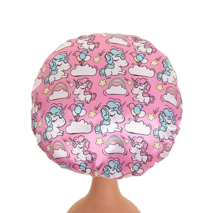 Detailed view of pink satin bonnet with cartoon unicorn and rainbow prints for kids