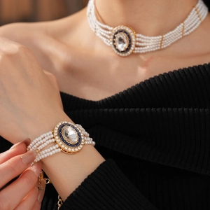 Detail of multi-layer pearl necklace and bracelet with blue enamel oval pendant