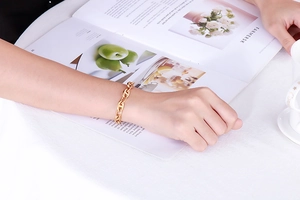 Detail of golden pig nose link bracelet worn by a model in a cozy cafe setting