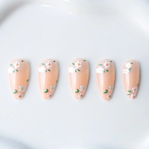 Almond press-on nails with delicate white daisy and green leaf floral patterns on nude base