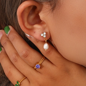Detailed view of teardrop pearl earrings with three diamonds and 18K gold plated finish