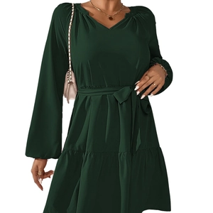 Elegante abito verde scuro a maniche lunghe con scollo a V, cintura e orlo a balze