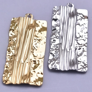 Detailed macro view of 18k gold and silver rectangle hammered pendants in 304 stainless steel