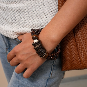 Detail of multi-layer coconut shell and wooden beaded bracelet worn on a female wrist
