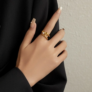 Detailed close-up of a vintage irregular gold wavy ring with a white pearl on a finger