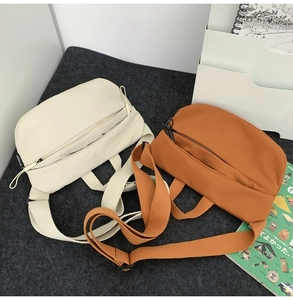 Minimalist nylon crossbody fanny packs in beige and orange on a grey felt mat background