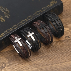 Detailed close-up of four woven leather bracelets with metal crosses on a wooden desk