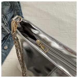 Detail of silver metallic handbag featuring premium golden chain strap and zipper