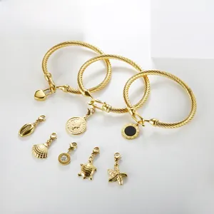 Macro detail of gold stainless steel braided bangles with heart and coin charms